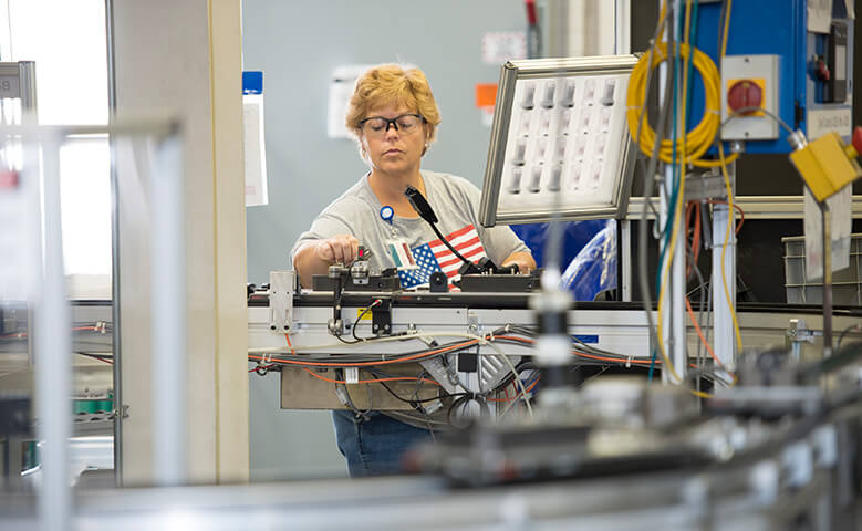 Woman working on product machinery with safety glasses on