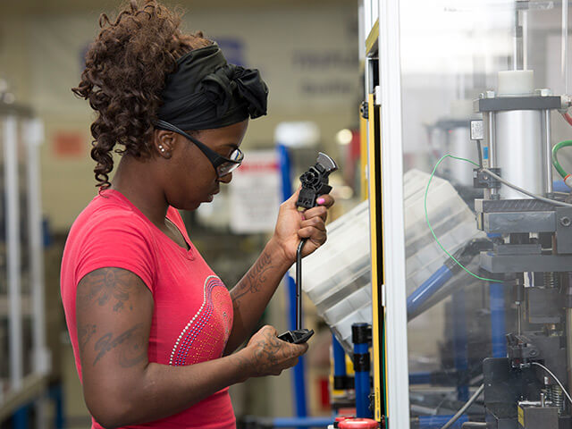 woman looking intently at pedal arm in front of machinery