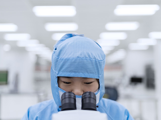 Person using microscope in full scrubs