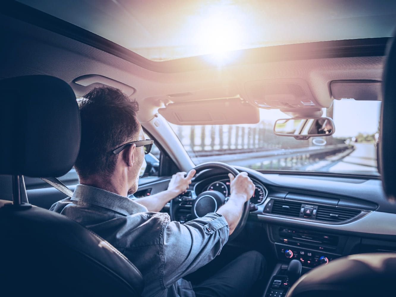 Man driving towards sunset