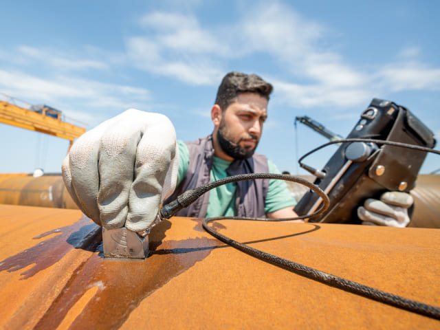 Engineer using ultrasonic accelerometer to monitor equipment vibration