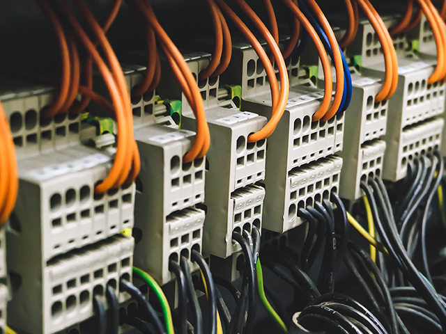 Electrical panel with orange wires going in and out of distribution blocks