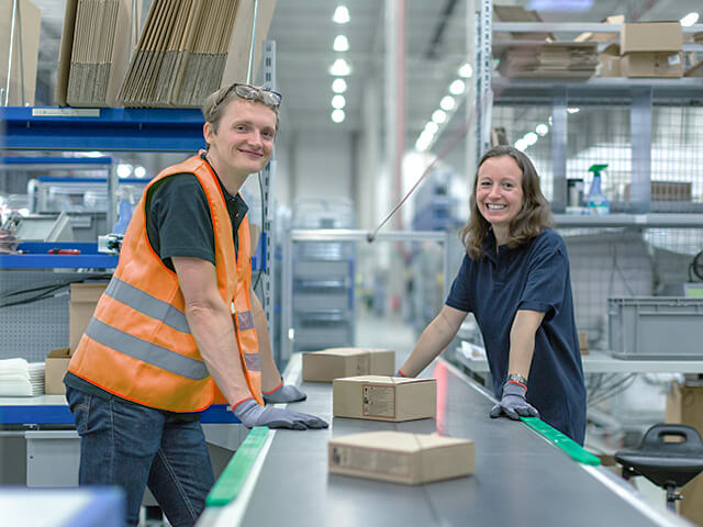 Smiling man and woman leaning on product assembly line
