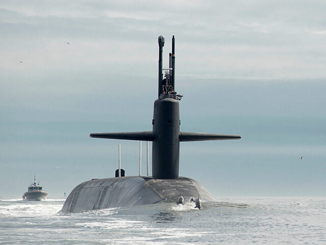 Submarine surfacing with dolphins jumping out of water