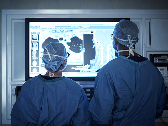 Doctors in full scrubs looking at medical screen