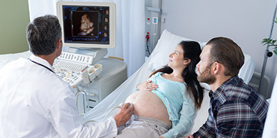 Ultrasound technician, man and woman looking at screen of 3D fetus