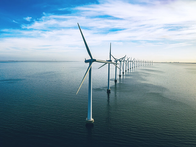 Windmills lined up next to each other in ocean