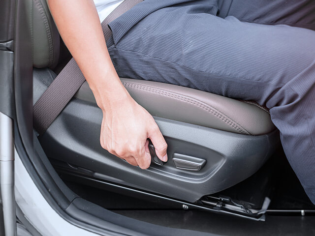 Man moving automatic seat using seat controls in car