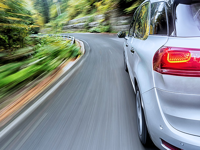 Car driving fast down road with greenery