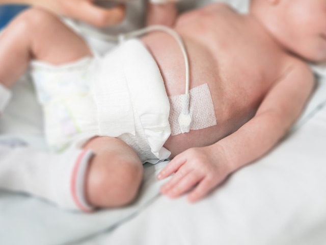 Baby with temperature sensor tapped to arm for monitoring